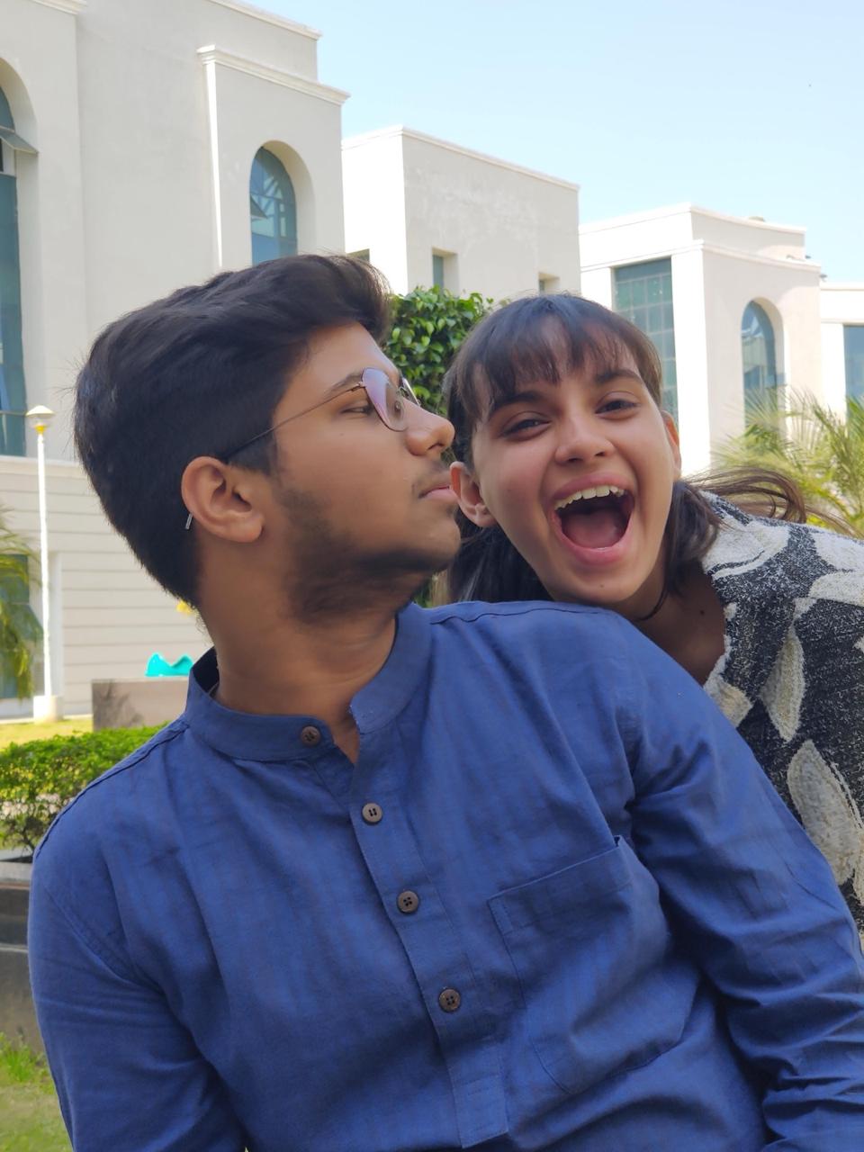 Vatsal in a blue kurta and Gunjan laughing behind him on a sunny campus