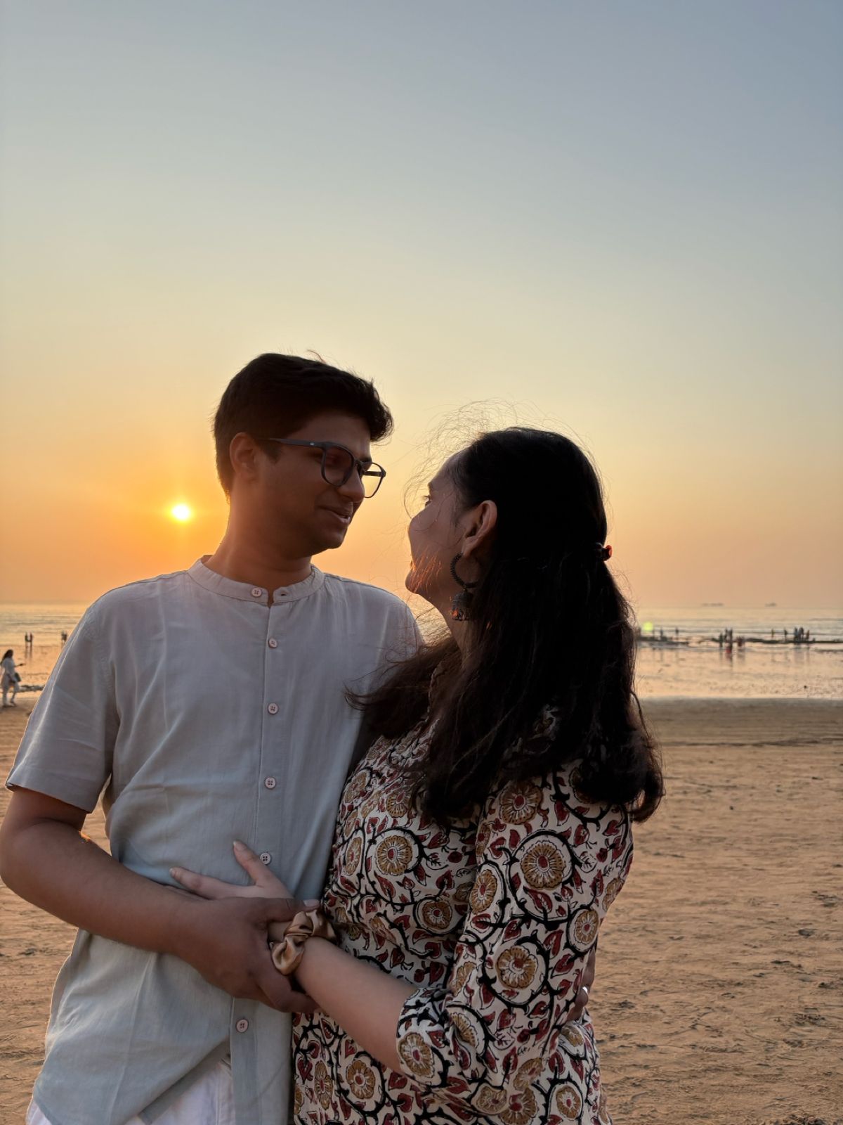Vatsal and Gunjan looking at each other on a beach at sunset