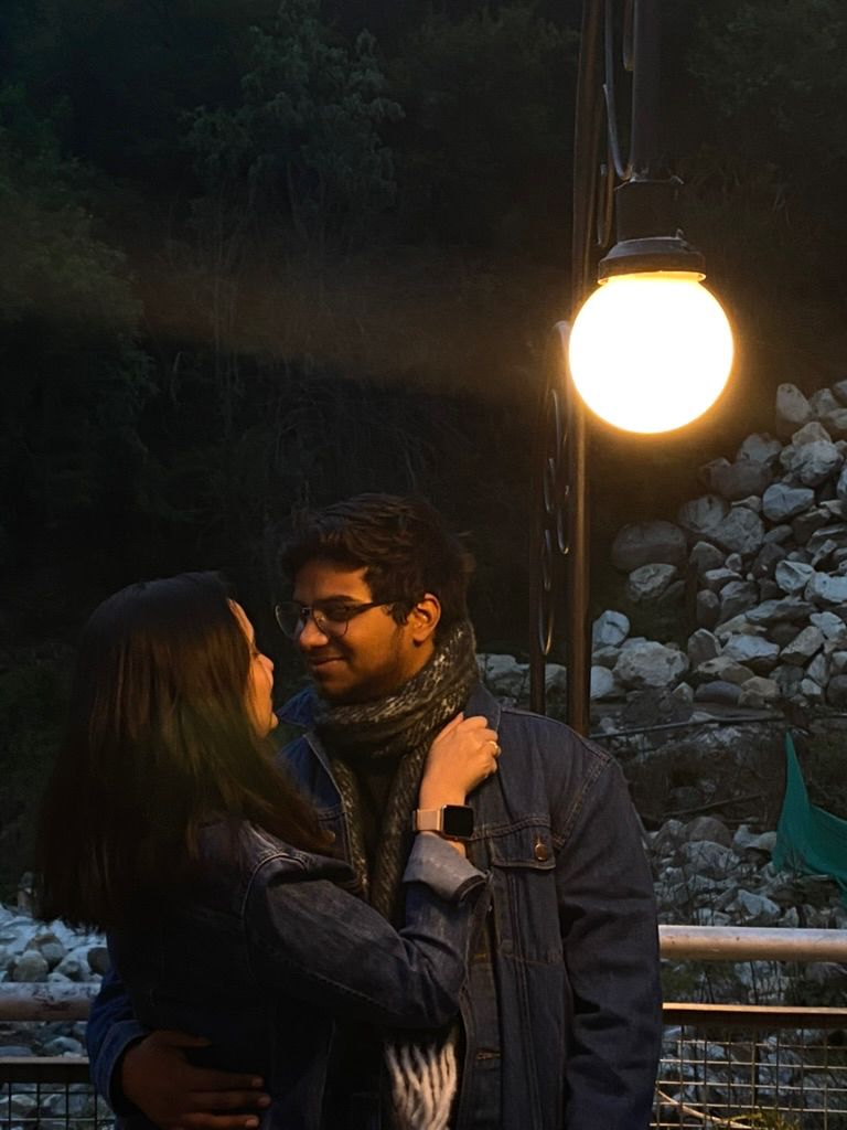 Vatsal and Gunjan in denim jackets under a glowing lamp in the hills at dusk
