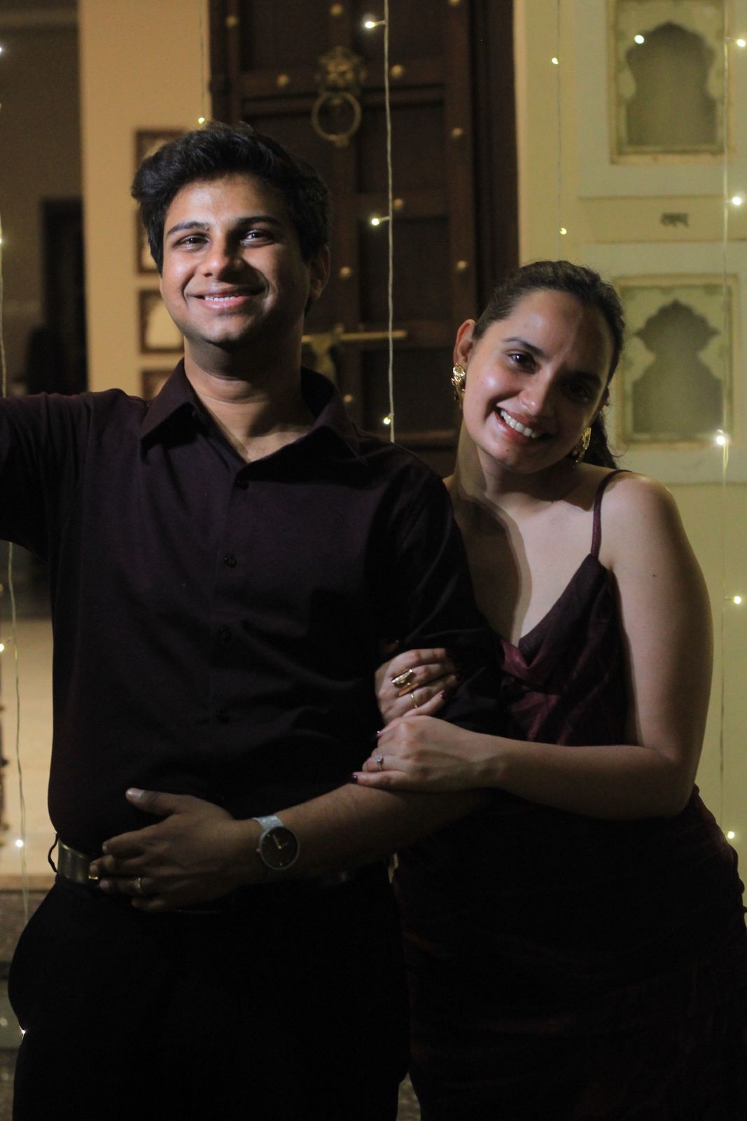 Vatsal and Gunjan smiling together in front of fairy lights